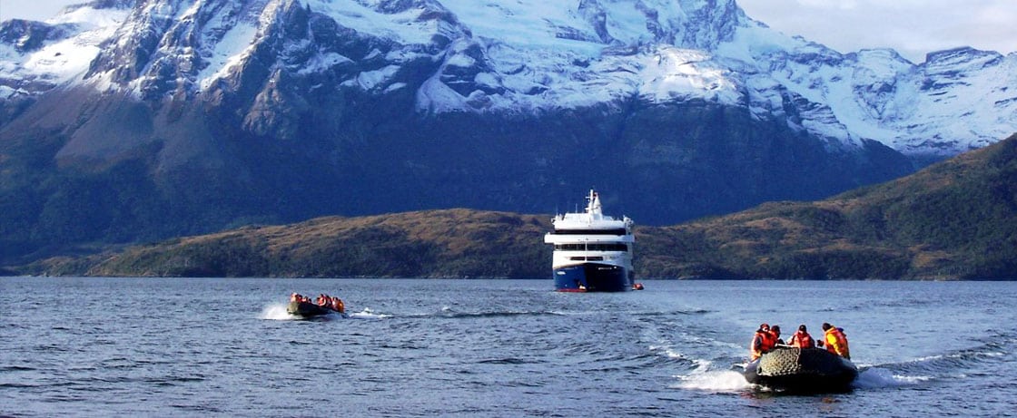 Une croisière de luxe avec TMR Voyages, au milieu des montagnes enneigées et des bateaux sur des eaux calmes.