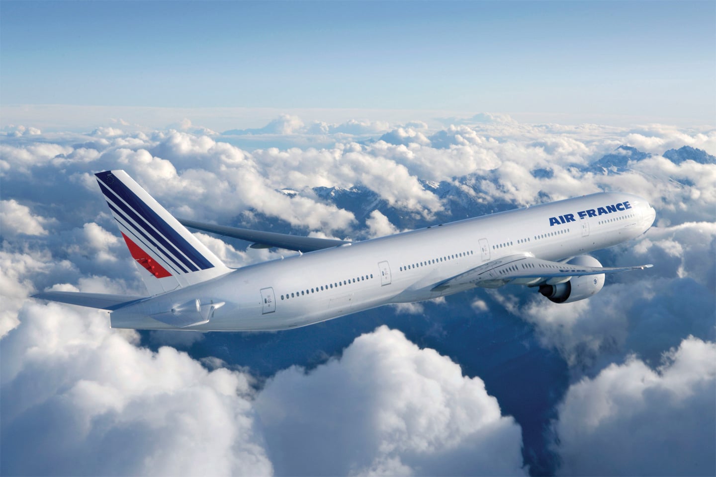Un avion Air France survole des nuages, symbolisant un voyage d’exception avec TMR Voyages vers des destinations exclusives.