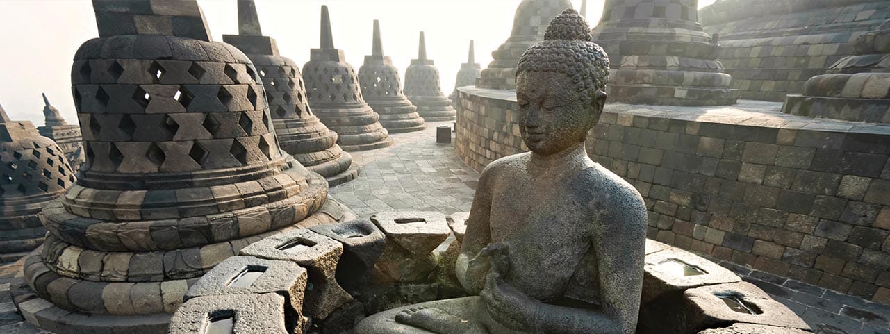 Bouddha en pierre au temple de Borobudur, symbole des découvertes culturelles en Indonésie. TMR Voyages pour une expérience authentique.