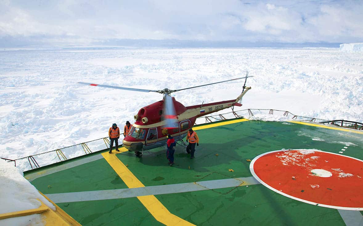 Hélicoptère sur une plateforme en Antarctique, offrant des expériences authentiques et des aventures inoubliables avec TMR Voyages.