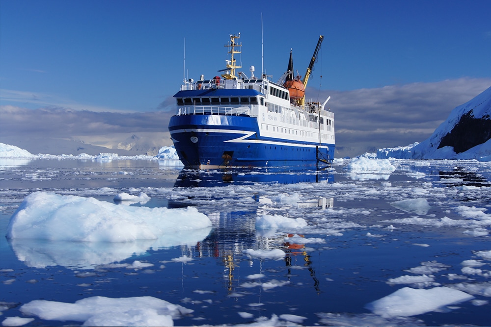 Un navire de croisière de luxe navigue parmi des icebergs, symbole d’expédition exceptionnelle avec TMR Voyages.