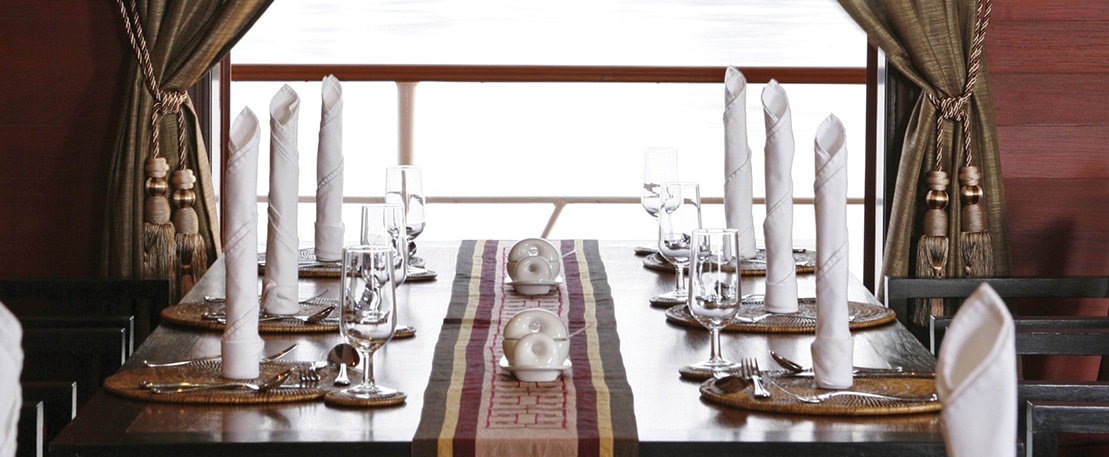 Une table élégamment dressée avec vue sur l'eau, parfaite pour un voyage de luxe avec TMR Voyages.