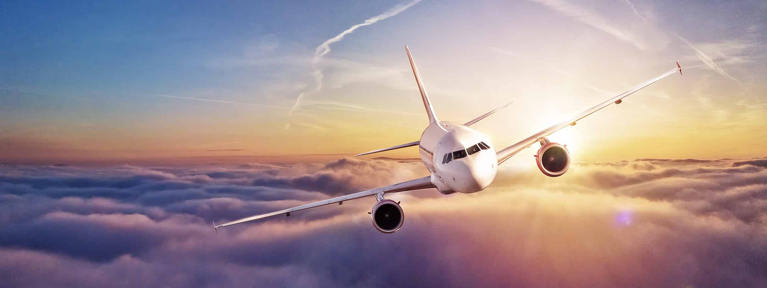 Un avion survole les nuages au coucher de soleil, symbolisant le voyage d'exception avec TMR Voyages.