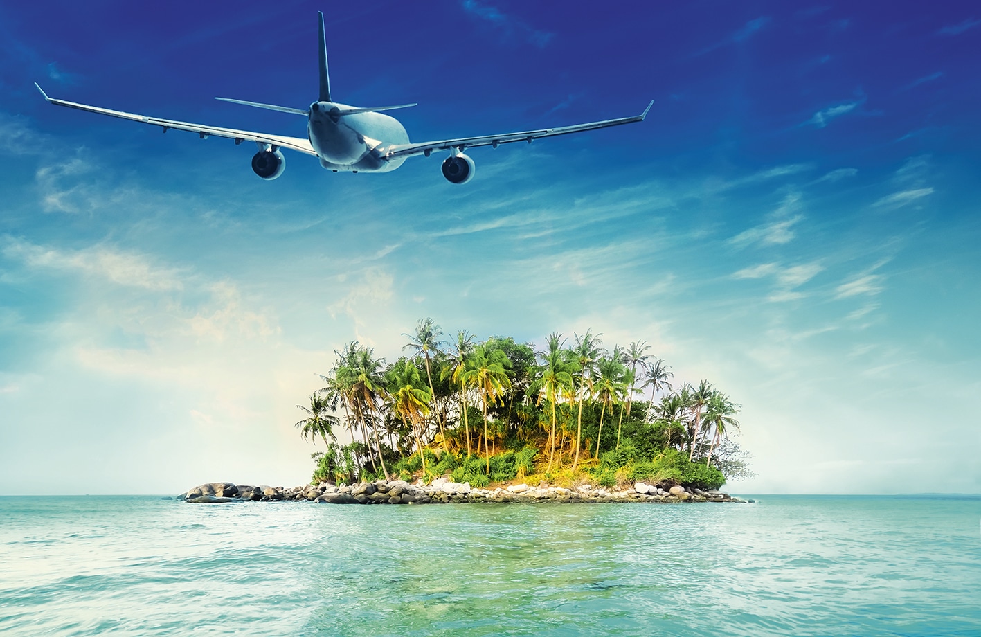 Un avion survole une île tropicale entourée d'une mer turquoise, idéale pour un voyage d’exception avec TMR Voyages.
