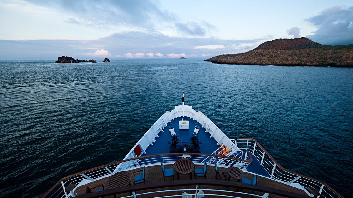 Vue panoramique depuis le pont d'un navire de croisière de luxe de TMR Voyages, avec des îles à l'horizon.