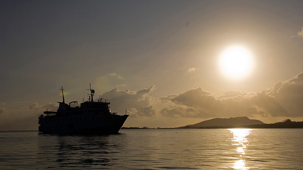 Un paquebot paisible sillonne les eaux dorées au crépuscule, une invitation au voyage de luxe avec TMR Voyages.