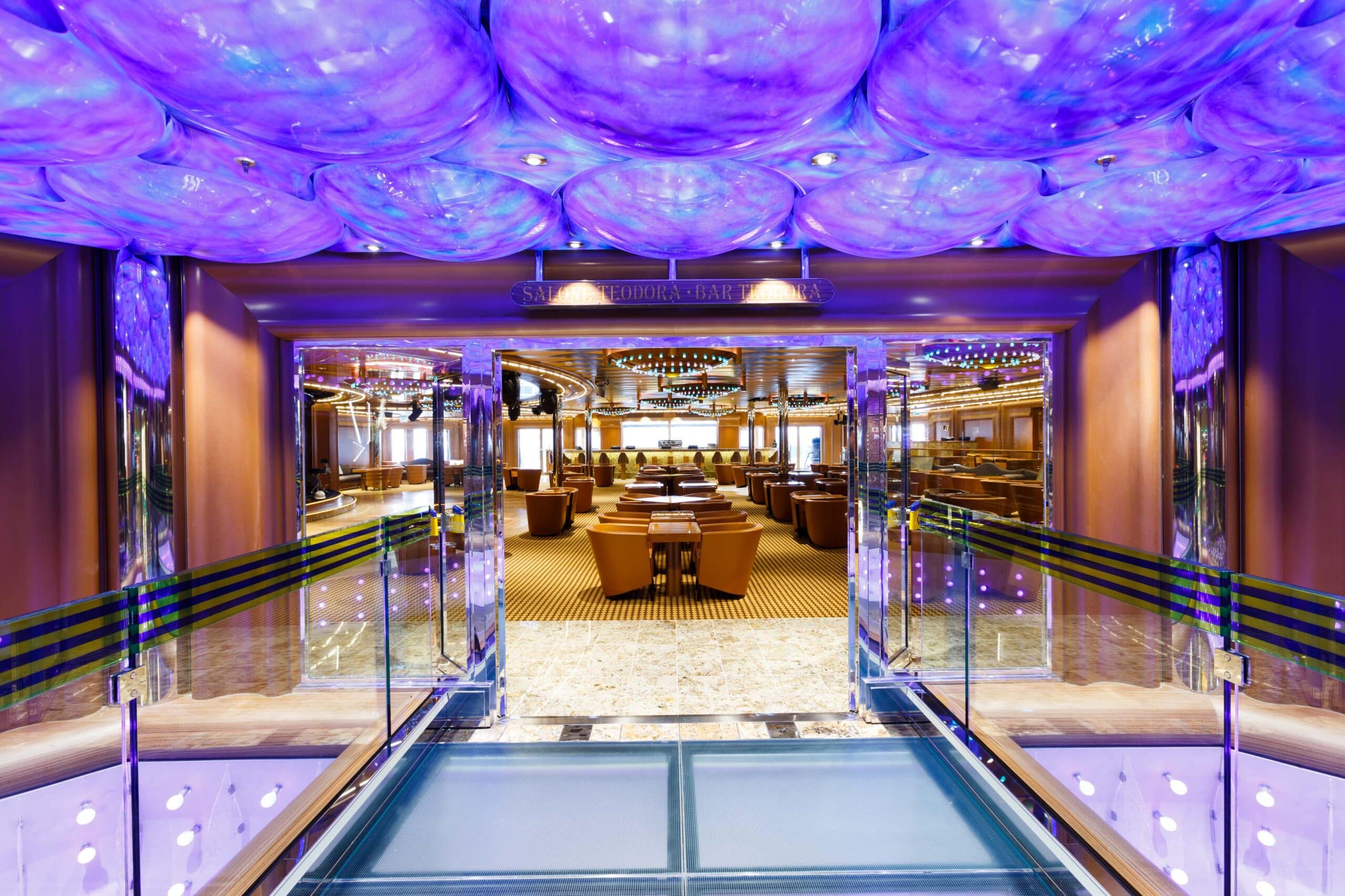 Un élégant salon de croisière avec un plafond violet, propice au voyage d’exception avec TMR Voyages.