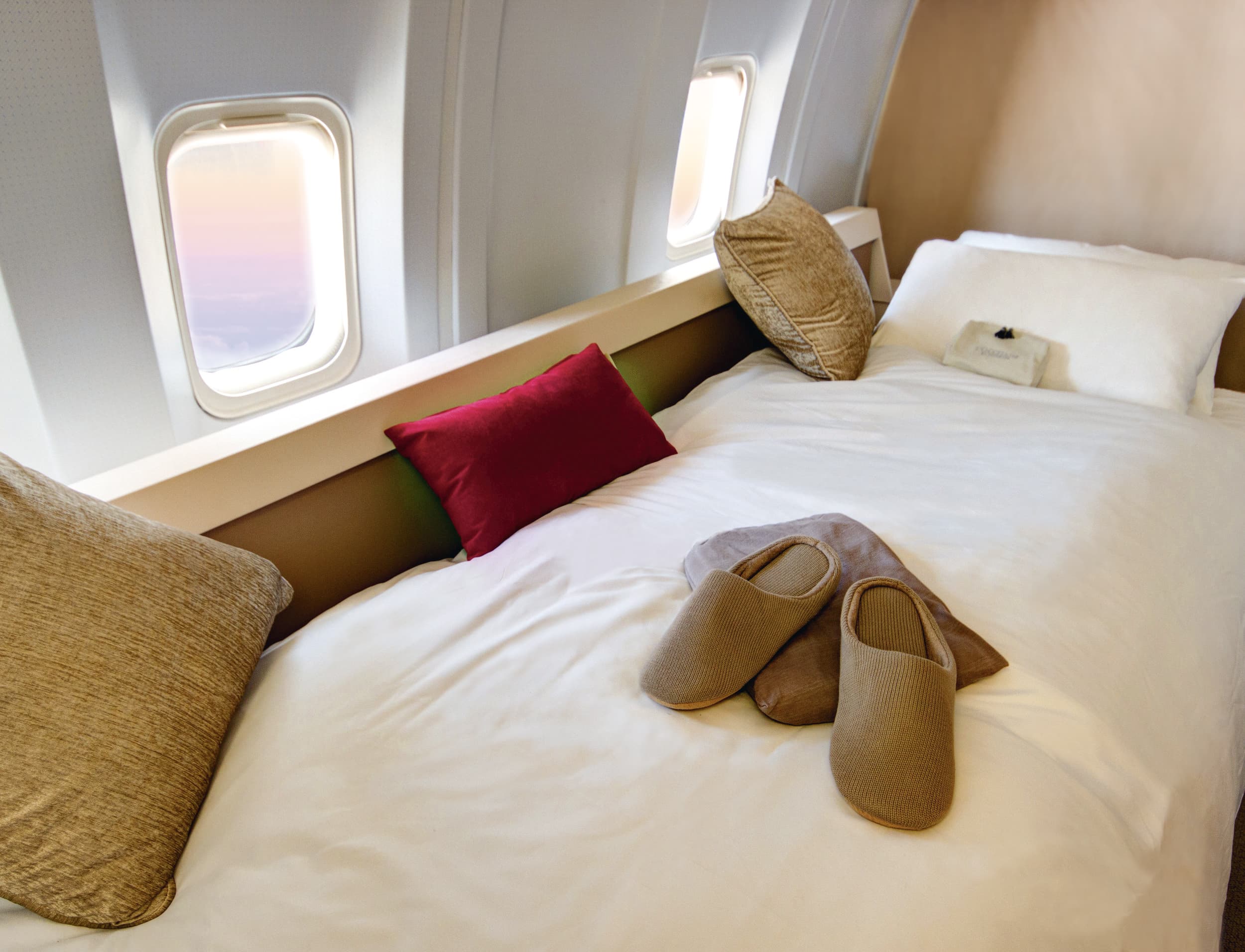 Chambre luxueuse dans un avion avec lit et coussins, idéale pour un voyage d’exception grâce à TMR Voyages.