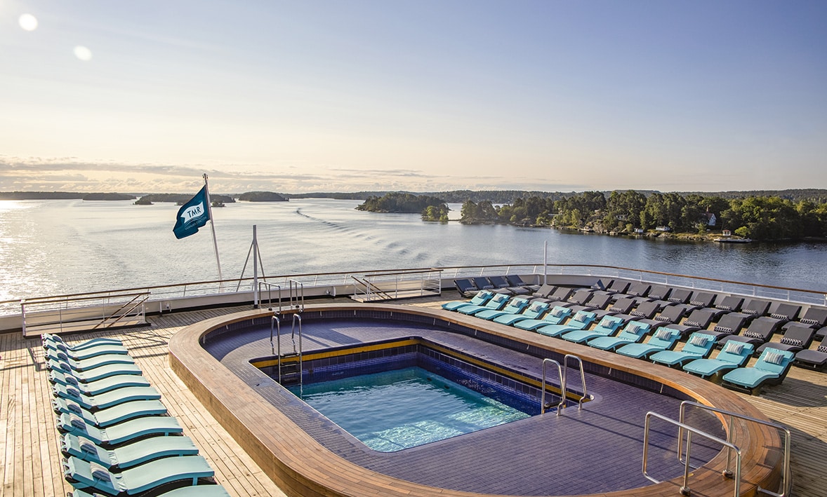 Sur un bateau de croisière de luxe, la piscine surplombe des paysages marins paisibles, offrant une expérience TMR Voyages.
