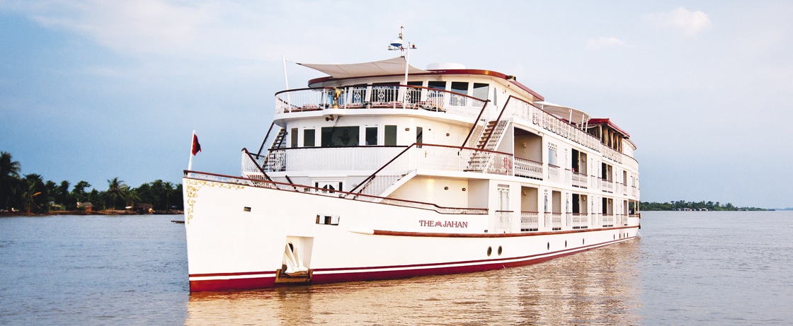 Un bateau de croisière de luxe, Jahan, navigue sur un fleuve, parfait pour un voyage d'exception avec TMR Voyages.