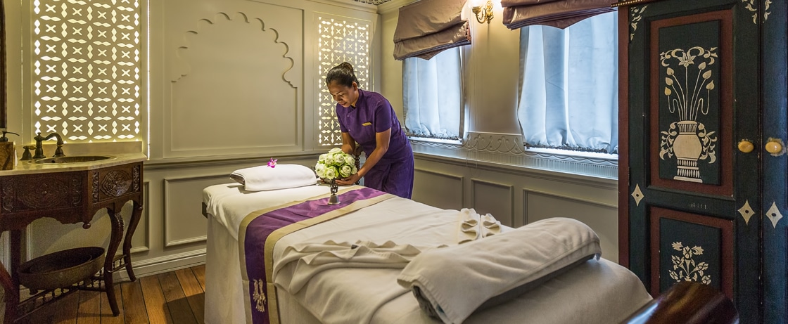 Un espace de spa raffiné avec un praticien préparant un massage, parfait pour un voyage de luxe avec TMR Voyages.