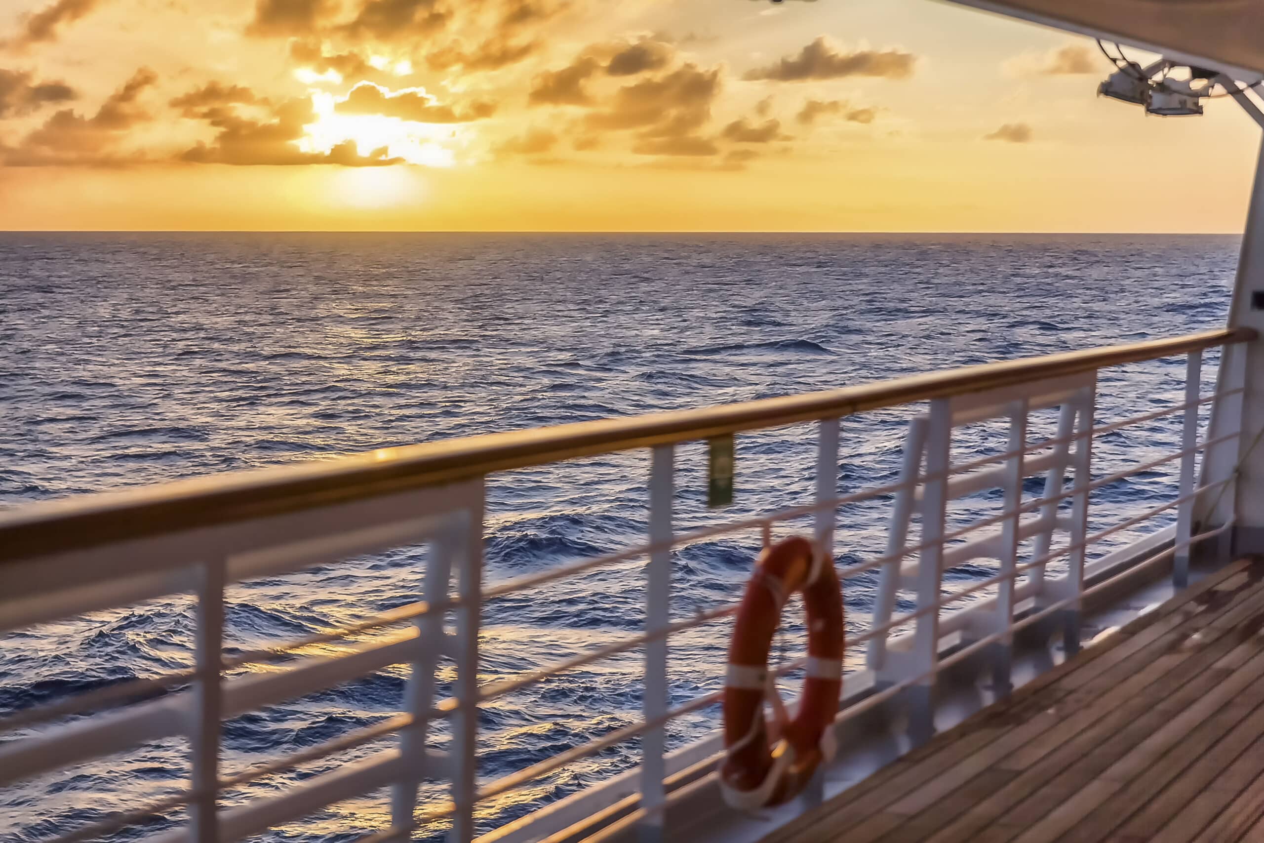 Un coucher de soleil doré vue depuis le pont d'un navire, invitant à une croisière de luxe avec TMR Voyages.