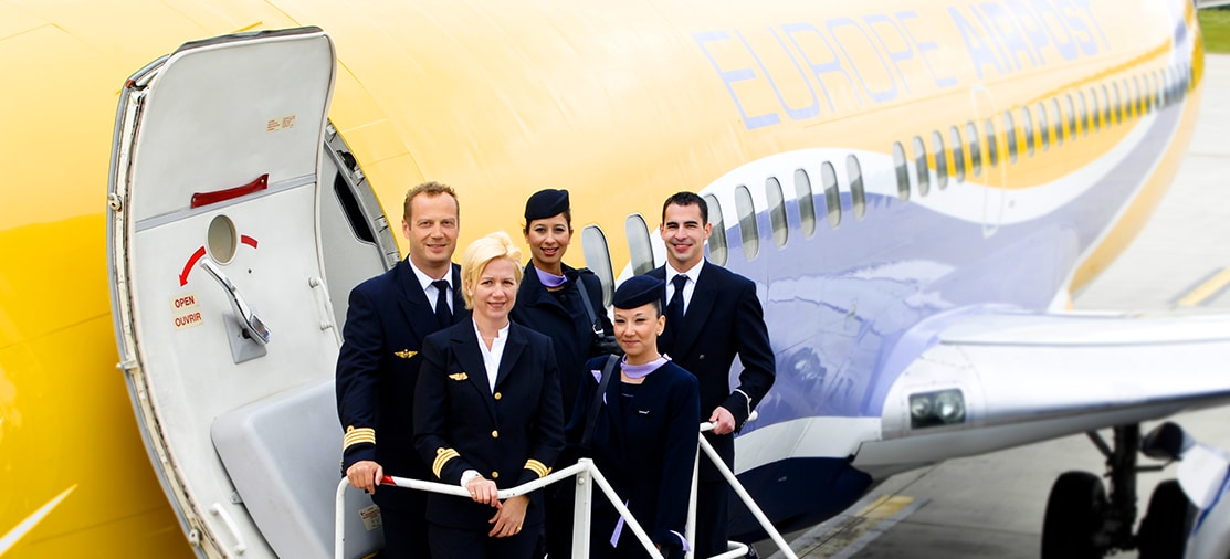 Un groupe d'équipage devant un avion Europe Airpost, symbole d'un voyage de luxe avec TMR Voyages.