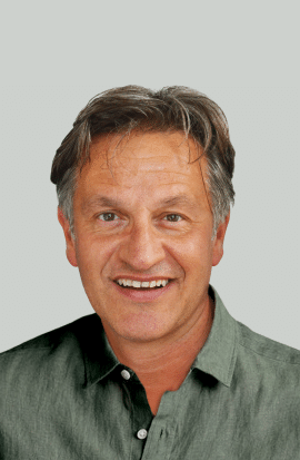Un homme souriant porte une chemise verte, représentant l'esprit d'aventure de TMR Voyages et de ses voyages d’exception.